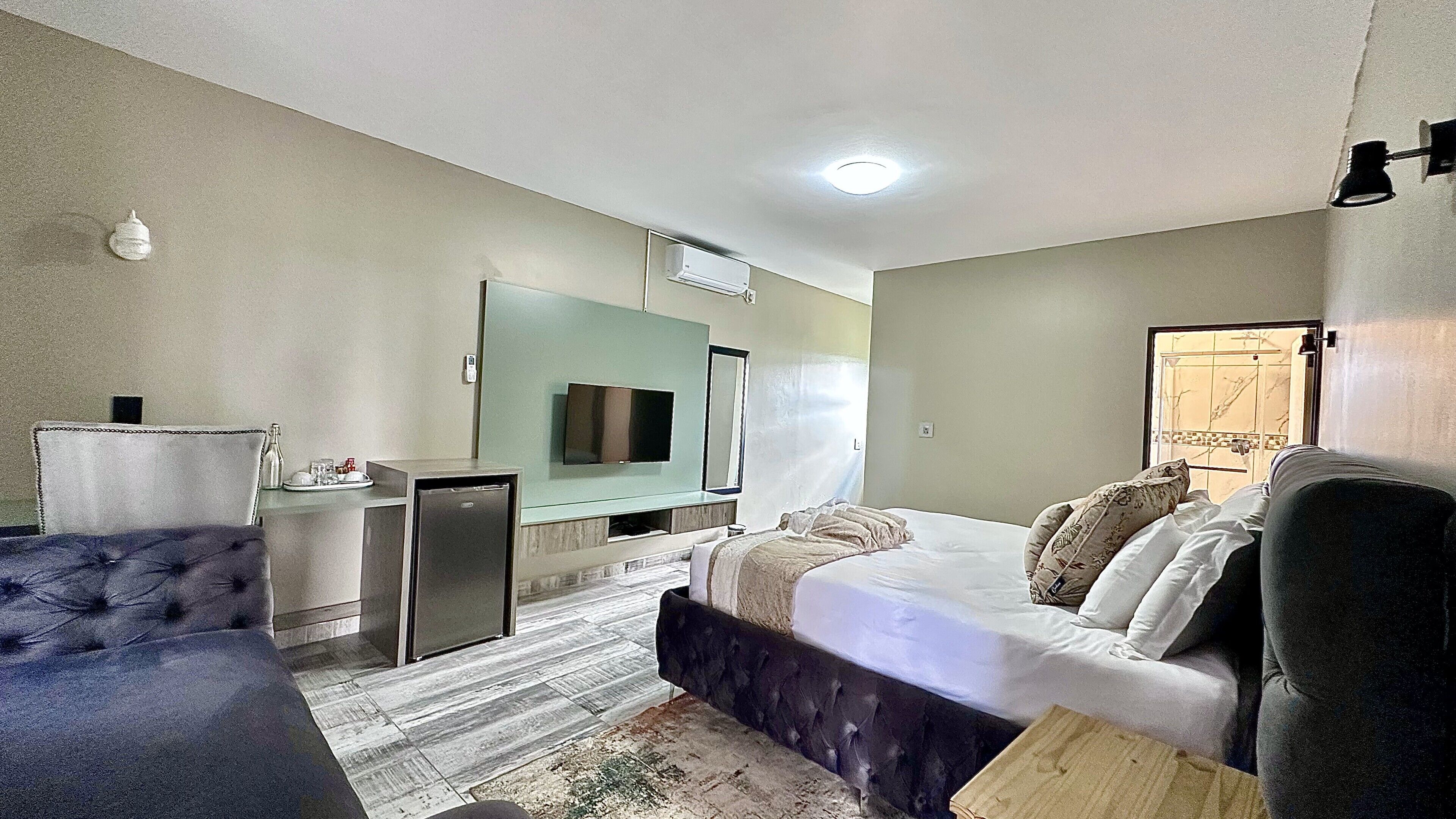 A hotel room with a bed, a desk, a television, and a small refrigerator.
