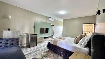 A hotel room with a bed, a desk, a television, and a small refrigerator.