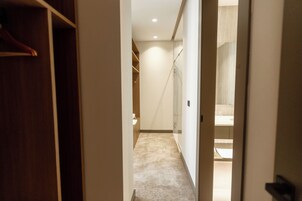 A hallway leading to a bathroom with a shower, a toilet, and a sink.