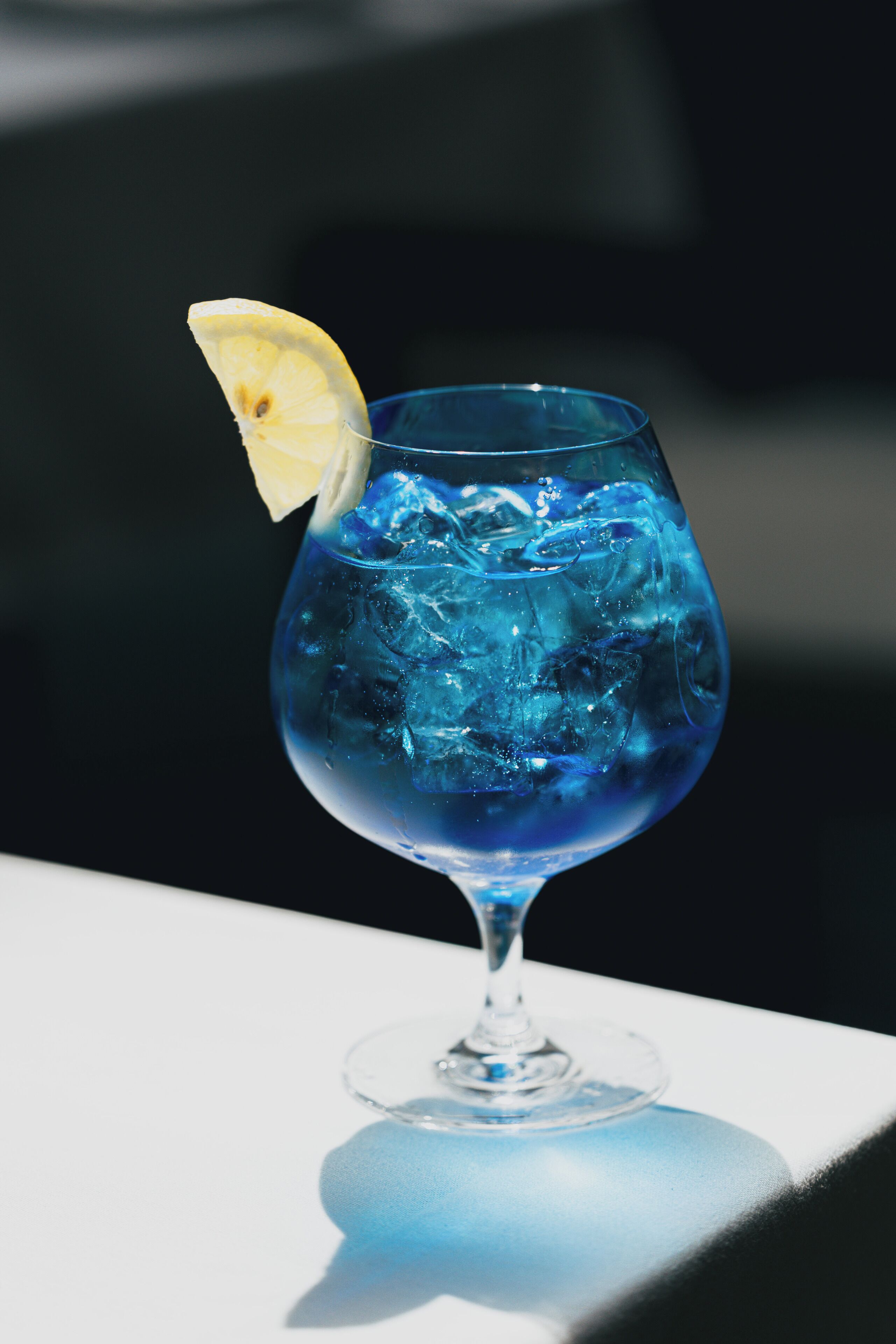 A glass with a lemon slice on a white surface.