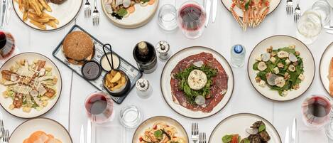 Una mesa dispuesta con varios platos, copas de vino y cubiertos.