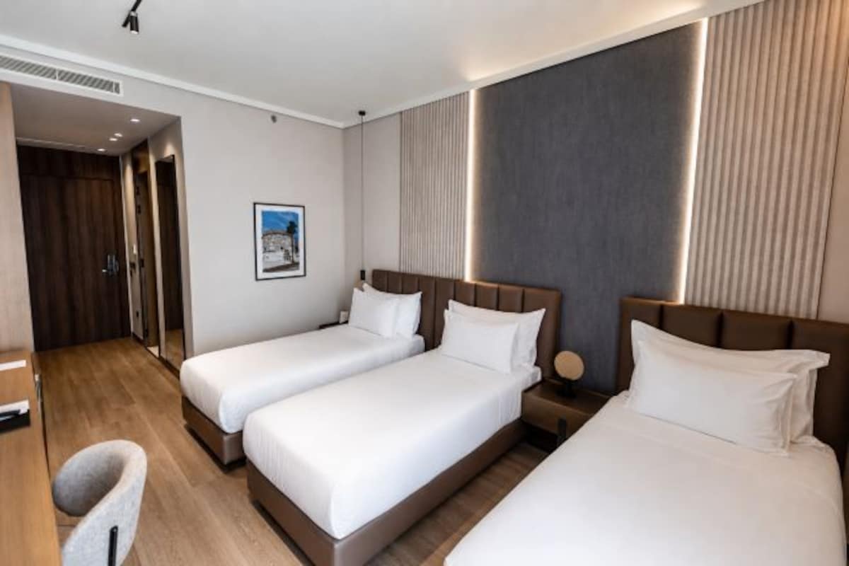 Una camera d'albergo con due letti, una scrivania e una sedia.