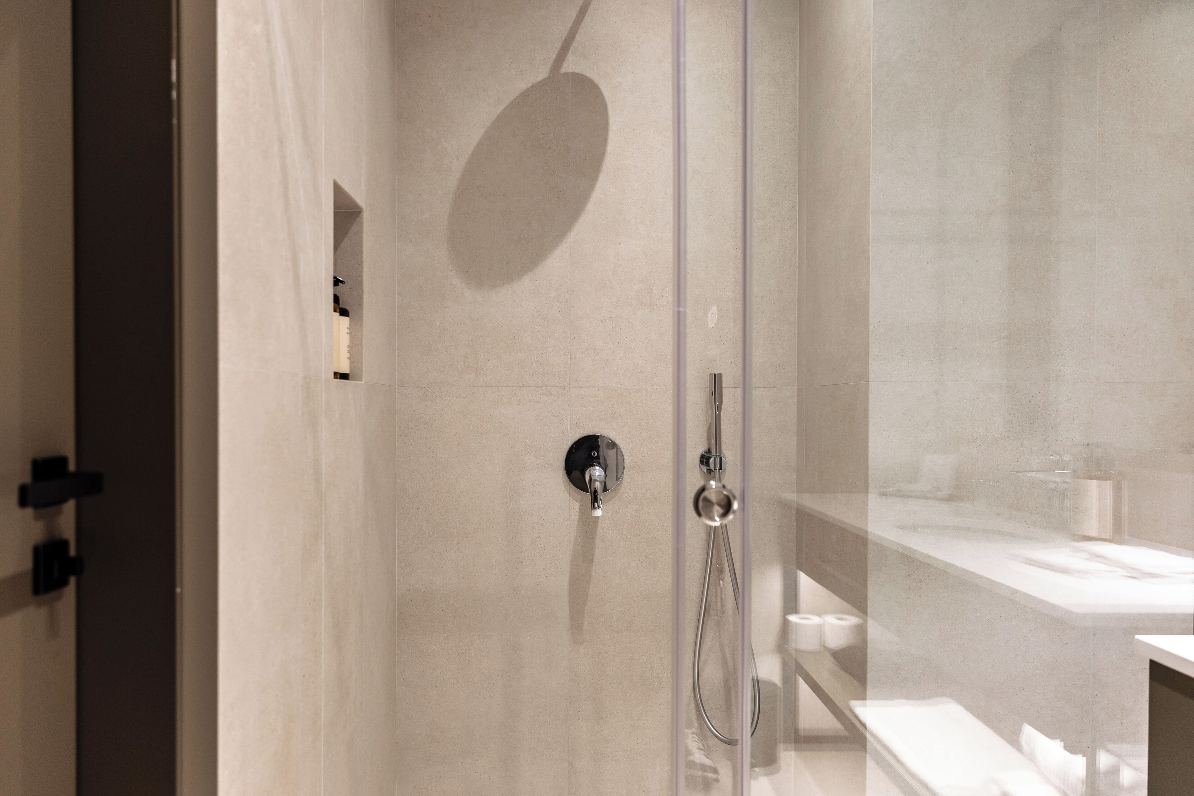 A modern bathroom with a glass shower enclosure, a visible towel rack, and a sink area.