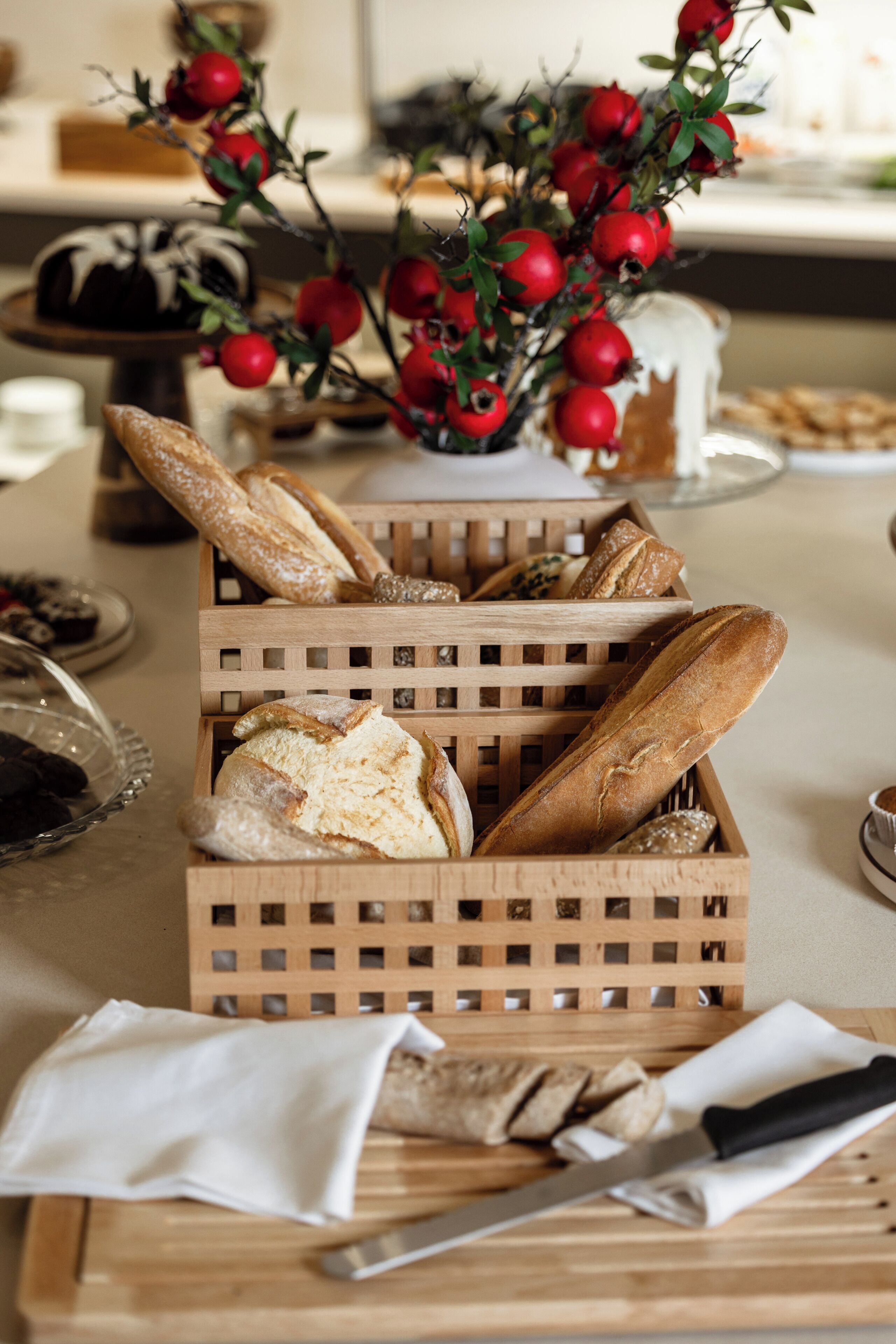 A wooden crate filled with various breads, a knife, and a cutting board on a table.