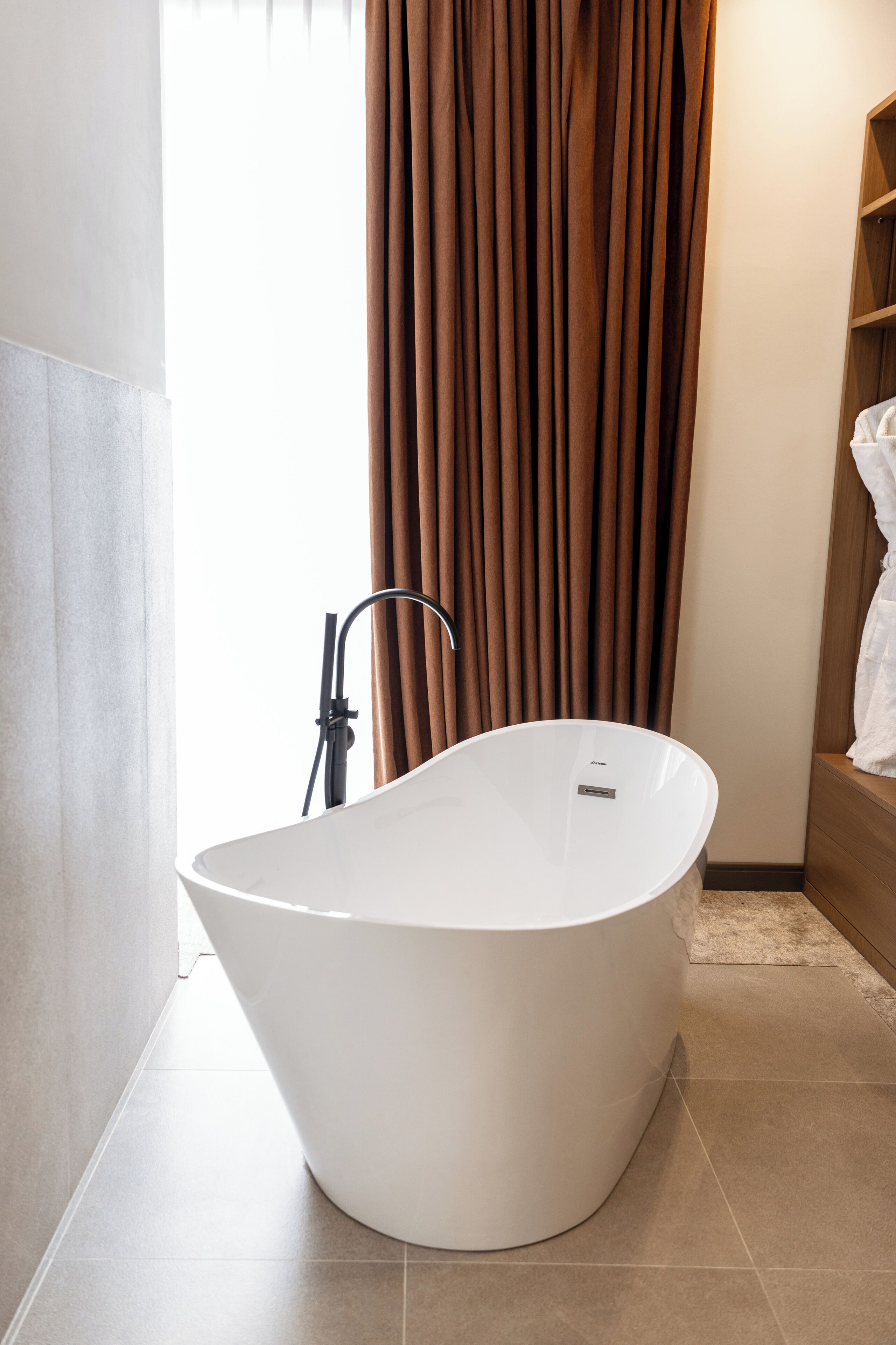 Een moderne badkamer met een vrijstaand bad, een douche en een houten plank met een handdoek.