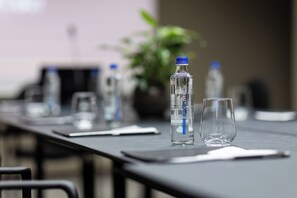 A conference table with water bottles and glasses, a laptop, and a potted plant in the background. - Grand Duka Hotel & Spa (Durrës)