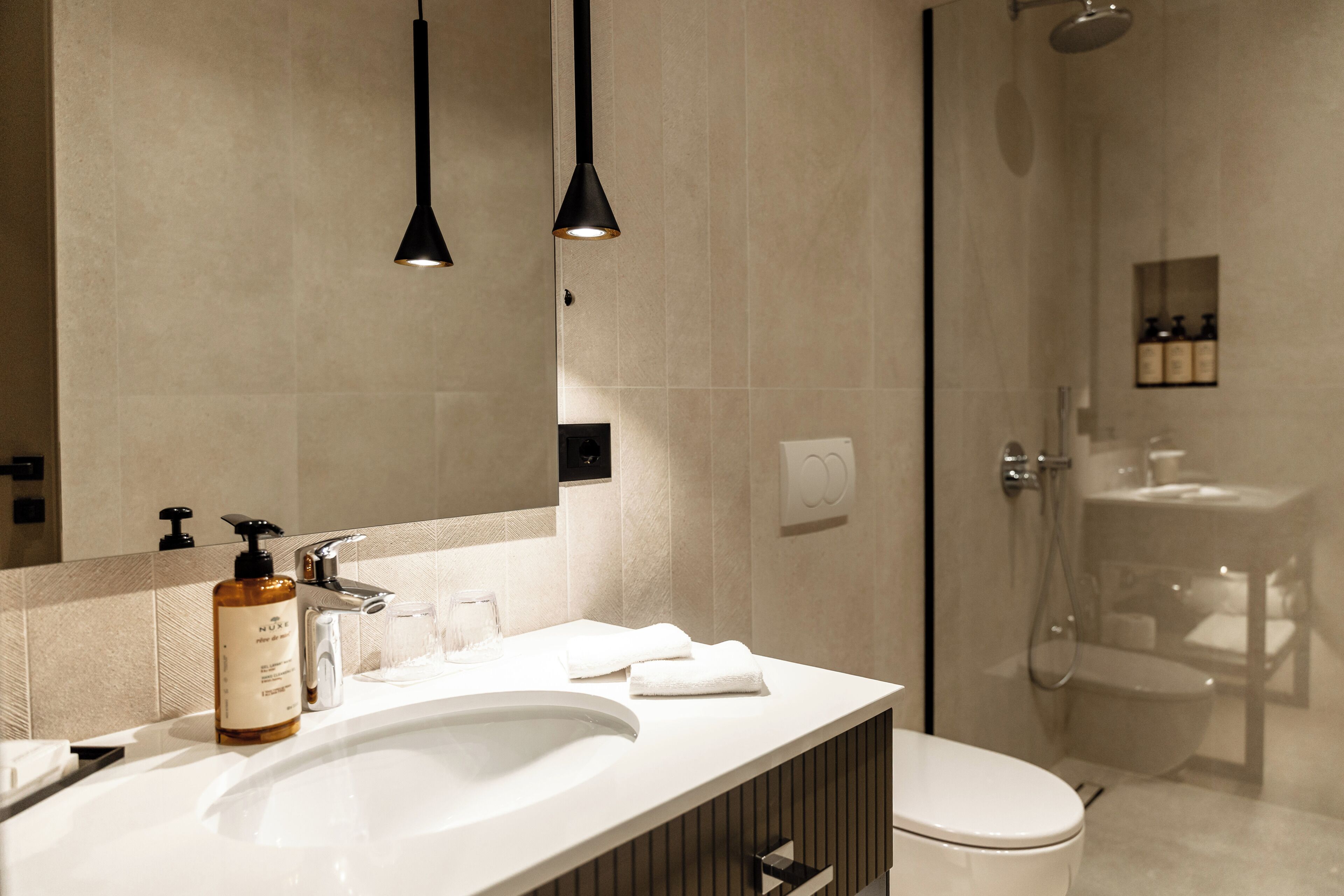 A modern bathroom with a large mirror, a sink, a toilet, and a shower.
