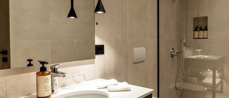 A modern bathroom with a large mirror, a sink, a toilet, and a shower.