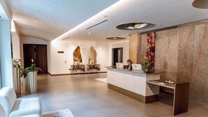 Eine moderne Hotelhalle mit Empfangsschalter, Sitzbereich und einer dekorativen Wand.