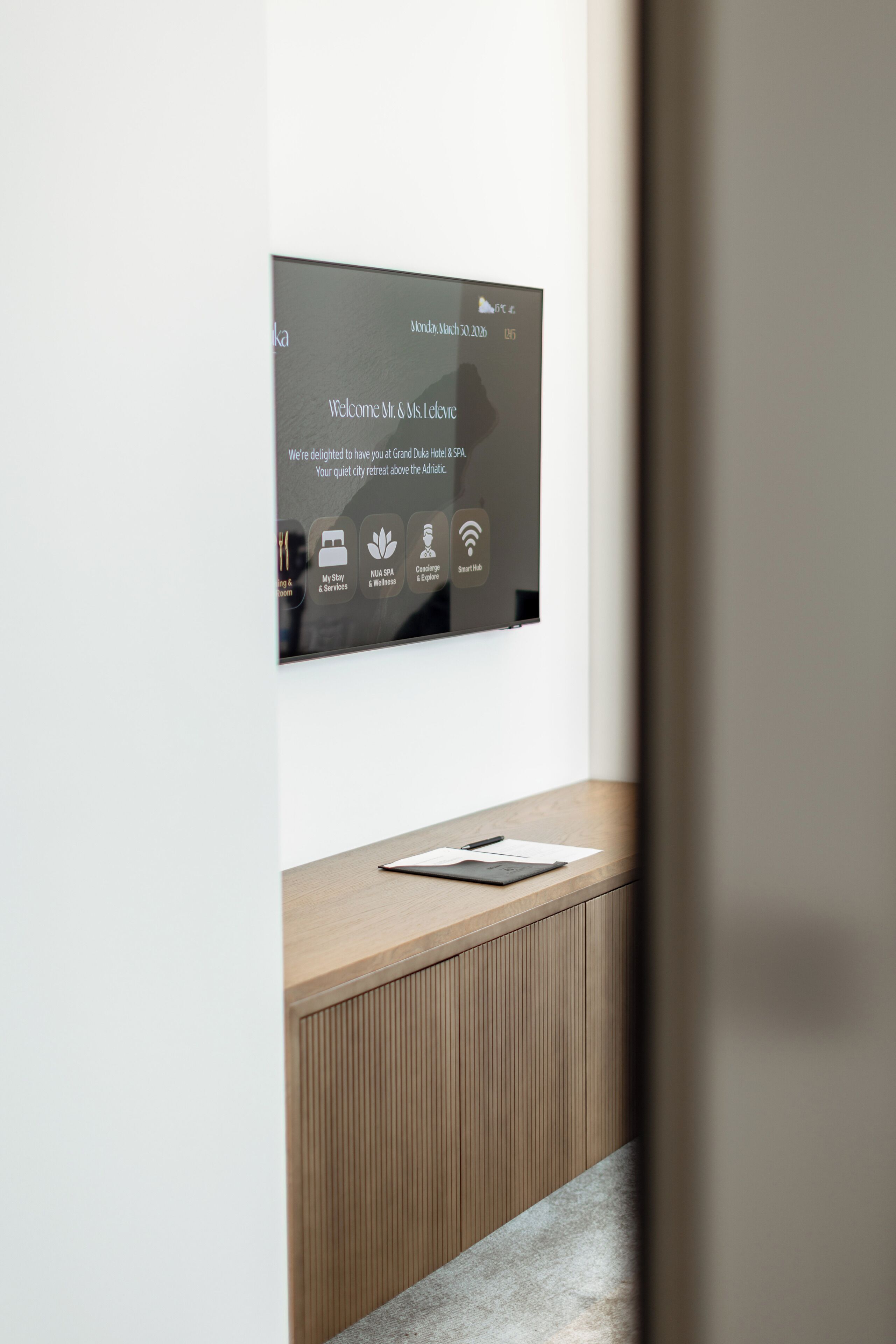 A modern reception desk with a digital screen displaying welcome messages and hotel amenities.