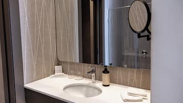 A bathroom with a white sink, a mirror, a towel, and a bottle of soap.
