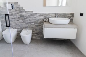 Un baño moderno con bidé, lavamanos y tocador.
