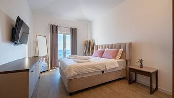 Une chambre d’hôtel moderne dotée d’un grand lit, d’une table de chevet, d’un téléviseur fixé au mur et offrant une vue sur l’extérieur.
