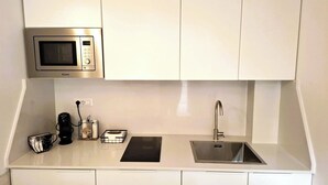 A compact kitchenette with a microwave, a sink, and a coffee maker. - CASA MORETTI (Bari)