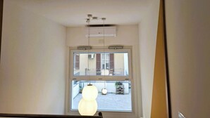 A room with a large window, an air conditioning unit, and a hanging light fixture. - CASA MORETTI (Bari)
