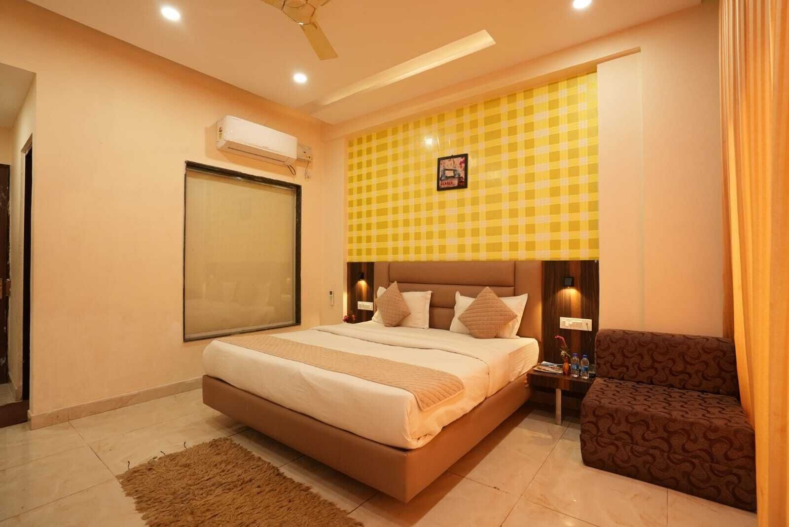 A bedroom with a bed, bedside tables, a chair, a window, and an air conditioning unit.