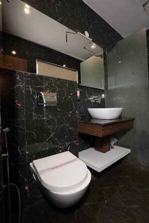A modern bathroom with a marble floor, a white toilet, a sink, and a mirror. - Royal suites Chakki Morh (Kasauli)