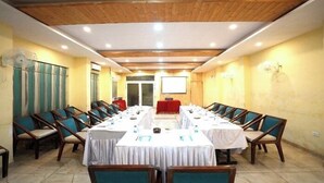A conference room with long tables and chairs, a projector screen, and a red table in the center. - Royal suites Chakki Morh (Kasauli)