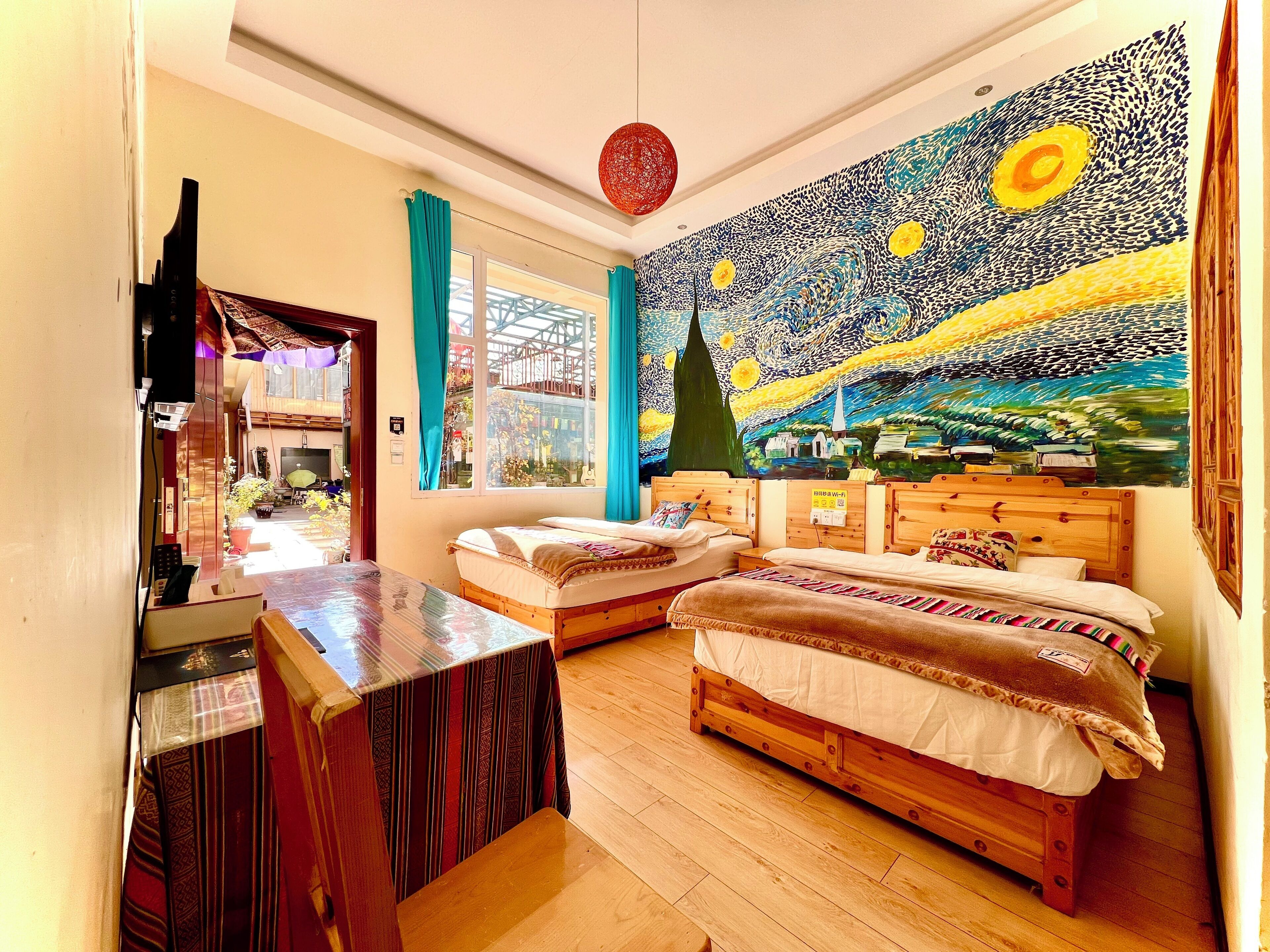 Een kamer met twee houten bedden, een klein tafeltje en een groot schilderij aan de muur.