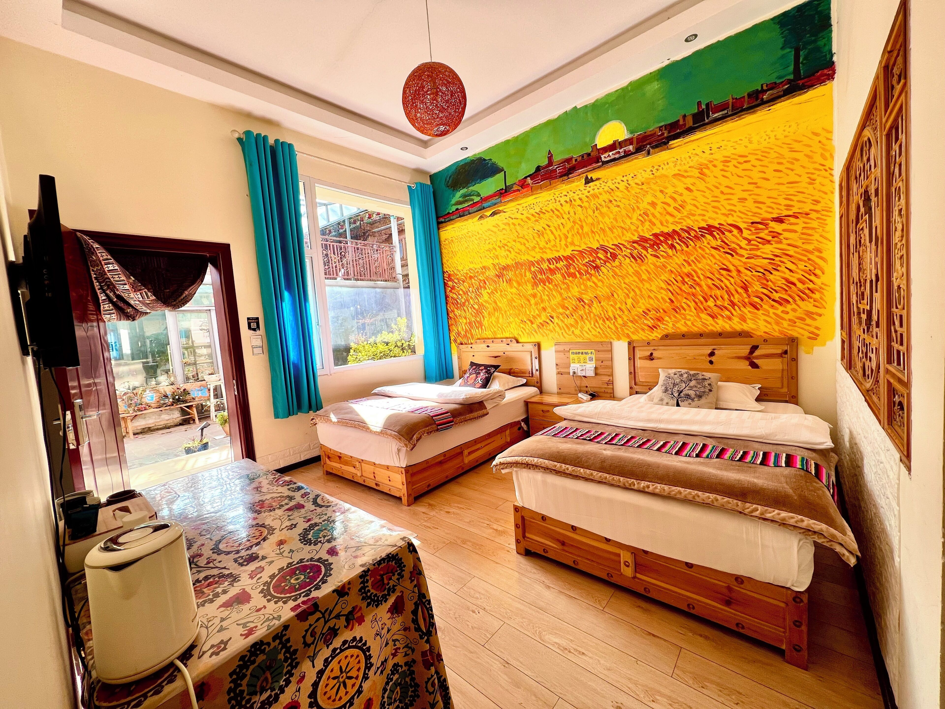 A hotel room with two beds, a table, and a view of a garden through a window.