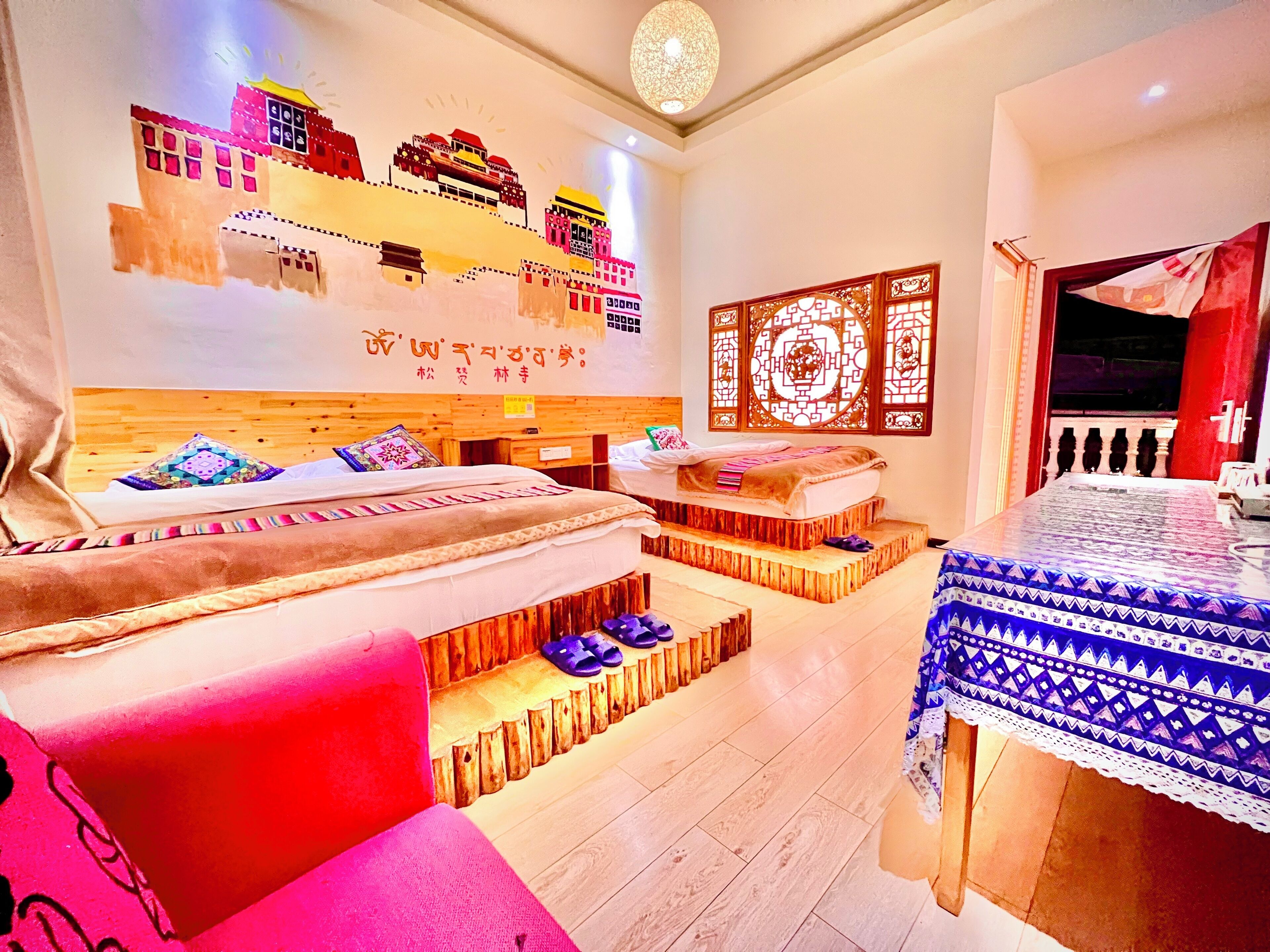 A hotel room with a large bed, a small table, and a decorative wall with a traditional design.