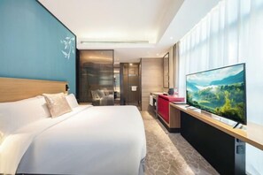 A hotel room with a large bed, a TV, a desk, and a view of a landscape. - Jingling Huatian Holiday Hotel (Capital Gymnasium Baishiqiao South Subway Station) (Beijing)