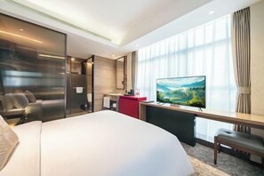 A modern hotel room with a large bed, a desk with a flat-screen TV, a seating area with a sofa, and a large window with curtains. - Jingling Huatian Holiday Hotel (Capital Gymnasium Baishiqiao South Subway Station) (Beijing)