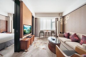 A modern hotel room with a large bed, a TV, a seating area with a coffee table, and a dining table with chairs. - Jingling Huatian Holiday Hotel (Capital Gymnasium Baishiqiao South Subway Station) (Beijing)
