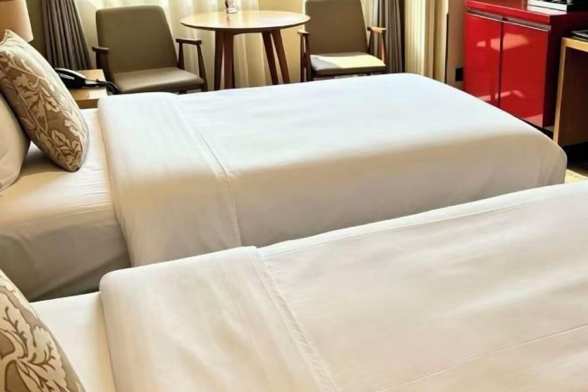 Una habitación de hotel con dos camas, una mesa redonda pequeña y un armario rojo.