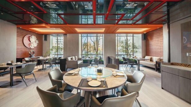 A modern conference room with round tables, comfortable seating, and large windows offering views of the outdoors.