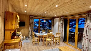 A cozy room with wooden walls and ceiling, a dining area with a table and chairs, a sofa, and a bench. - Residences Delavay (Les Gets)