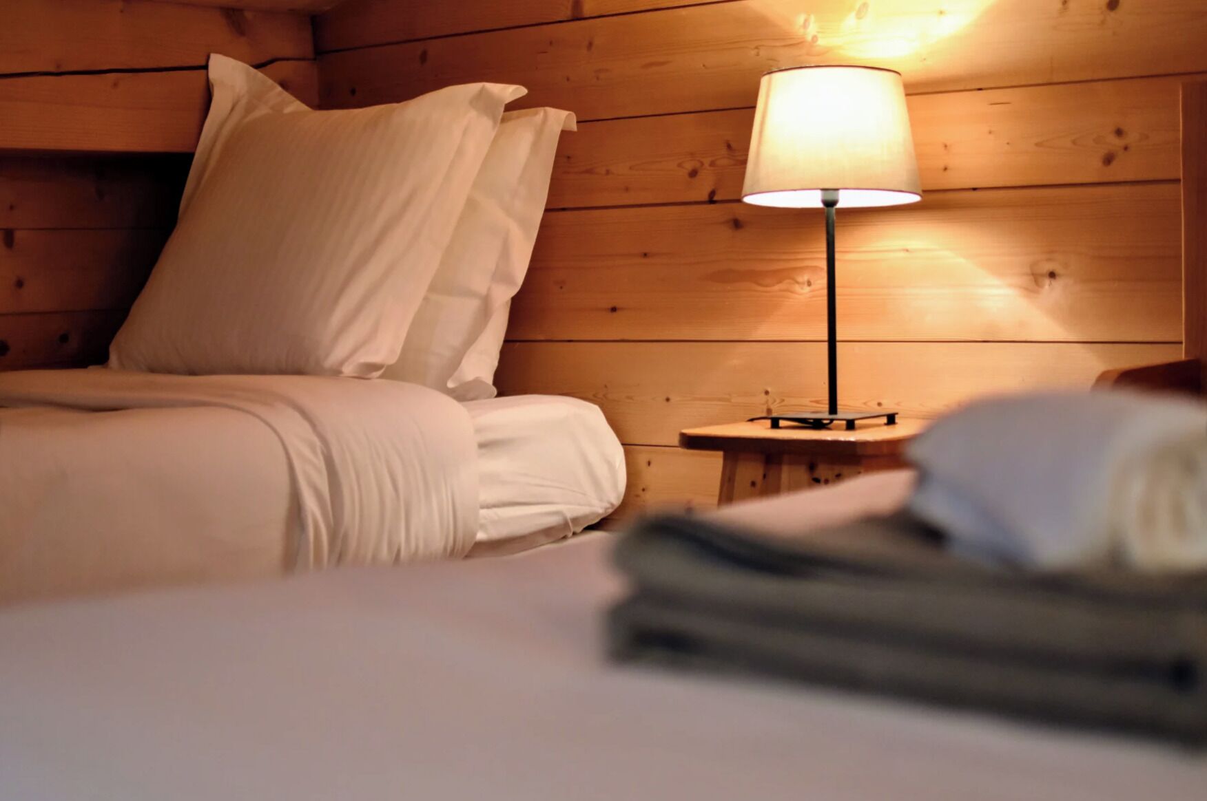 Ein Zimmer in einer Holzhütte mit einem Bett, einem Nachttisch und einer Lampe.