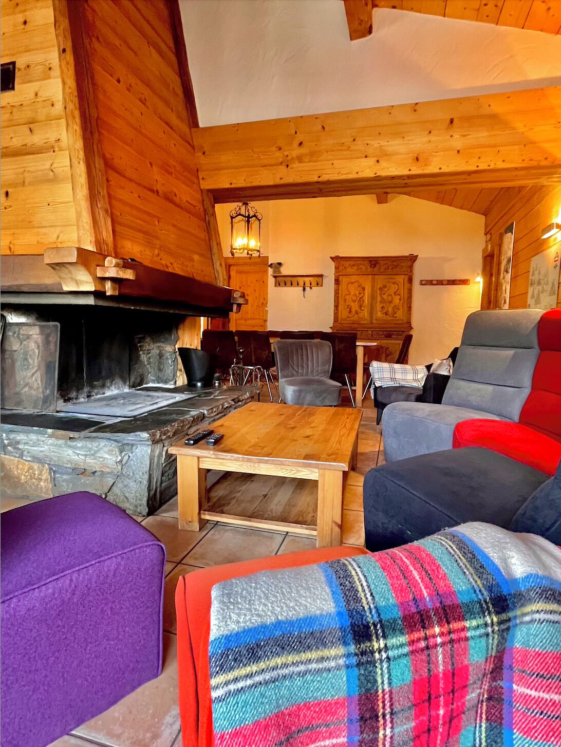 A cozy log cabin interior with a stone fireplace, wooden furniture, and a plaid blanket.