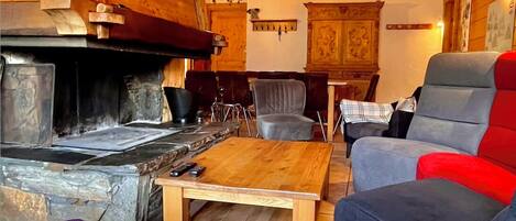 A cozy log cabin interior with a stone fireplace, wooden furniture, and a plaid blanket.