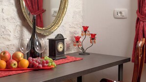 A dining area with a wooden table, a red velvet chair, a vintage clock, a mirror with a red curtain, and a chandelier. - Sun Spalato Ammarulla (Split)