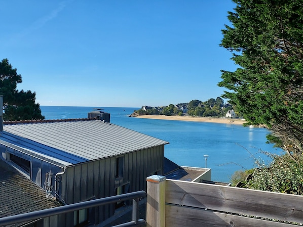 A coastal view with a clear sky, a sandy beach, and a body of water.