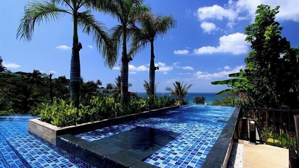A pool with clear blue tiles, surrounded by palm trees and a view of the ocean. - Panoramic View The Heights Kata Beach B1 (Muang)