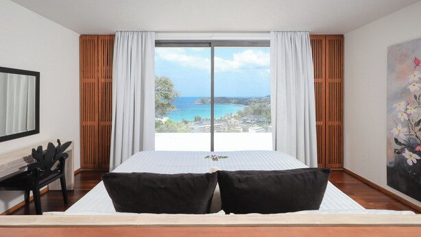 Une chambre avec un grand lit, un bureau et une vue sur la mer.