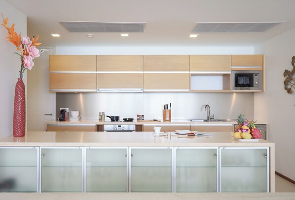 Una cocina moderna con armarios de madera, un microondas y una isla central con un frutero.