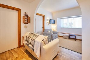A cozy bedroom with a bed, a chair, a small table, and a TV mounted on the wall. - Host Stay Spinnaker (Alnwick)