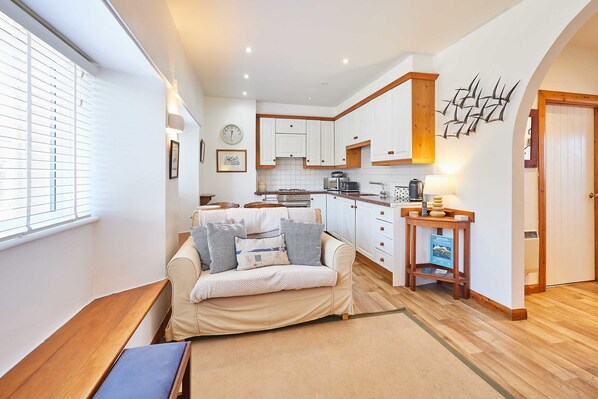 A compact living space with a sofa, a small table, and a kitchenette. - Host Stay Spinnaker (Alnwick)