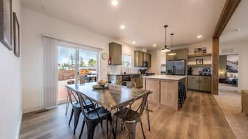 A modern kitchen with a central island, dining area with chairs, and a view of the backyard.
