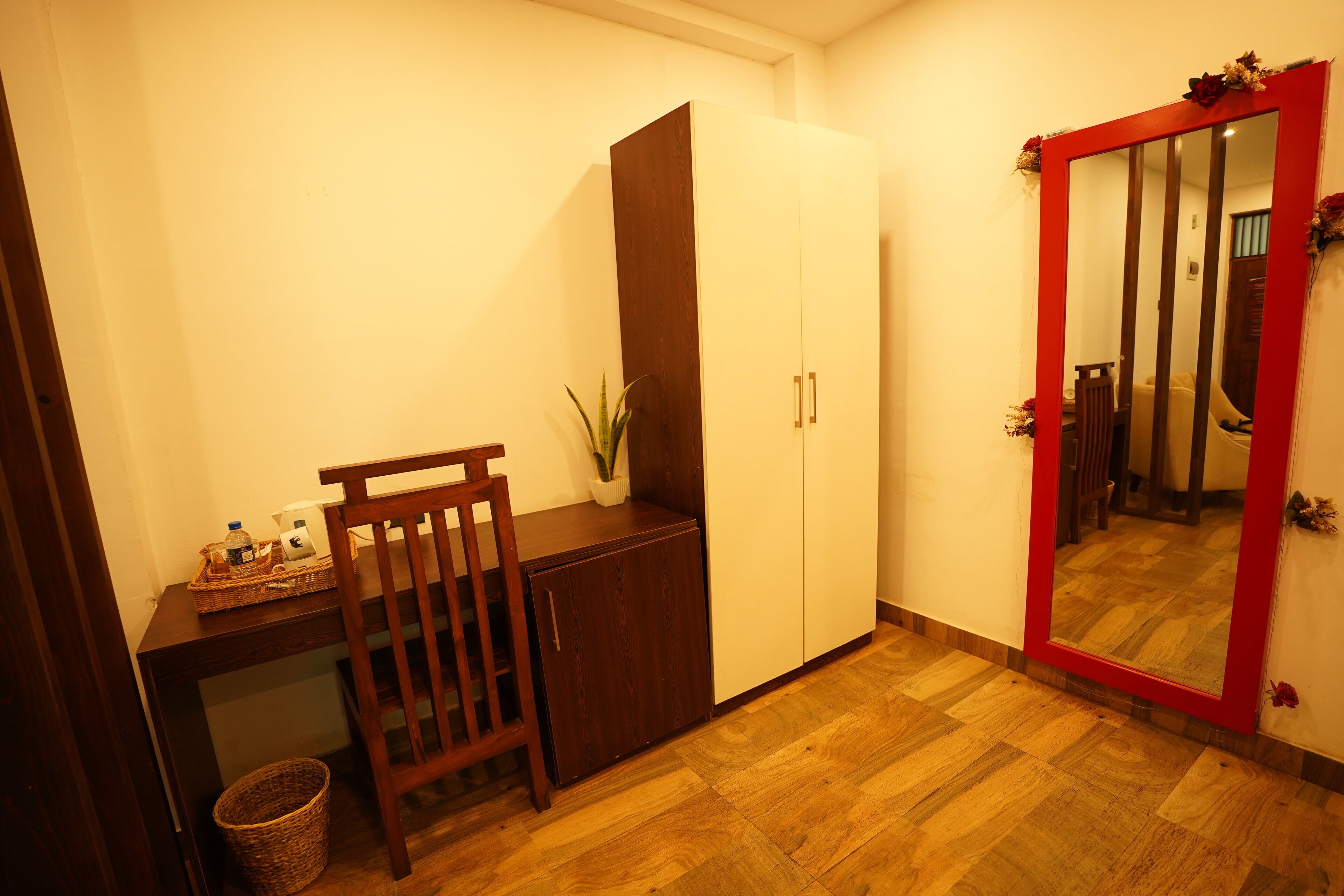 A room with a wooden desk, a chair, a cabinet, and a mirror with a red frame.