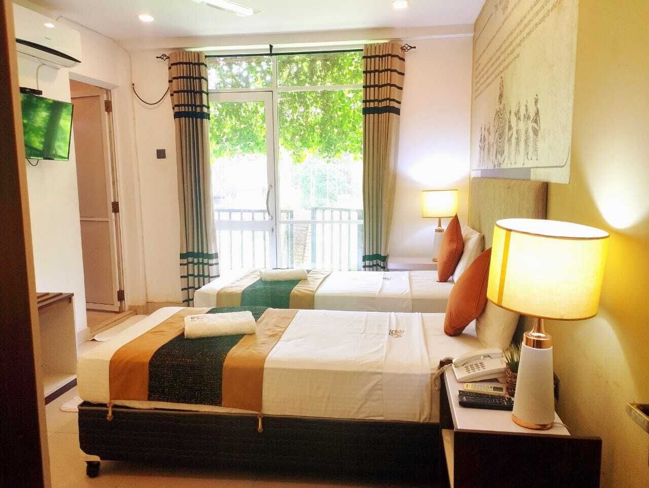 Une chambre d’hôtel avec deux lits, une télévision, une lampe et une vue sur l’extérieur.