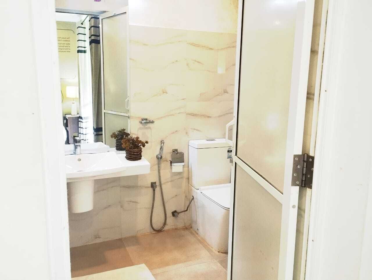 A compact bathroom with a white sink, a mirror, a toilet, and a shower area.