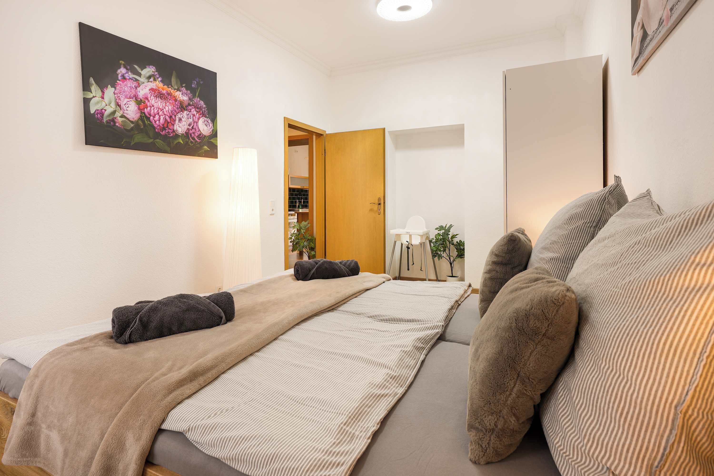 A bedroom with two beds, a painting, a wooden door, and a mirror.