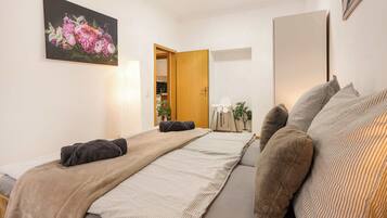 A bedroom with two beds, a painting, a wooden door, and a mirror.