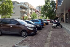 A row of parked cars and a scooter on a brick-paved street with buildings in the background. - Yeste Hotel (Yulin Culture Square) (Yulin)
