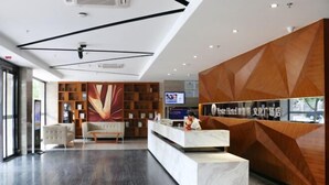 A modern reception area with a marble reception desk, wooden shelving, and a large abstract painting. - Yeste Hotel (Yulin Culture Square) (Yulin)