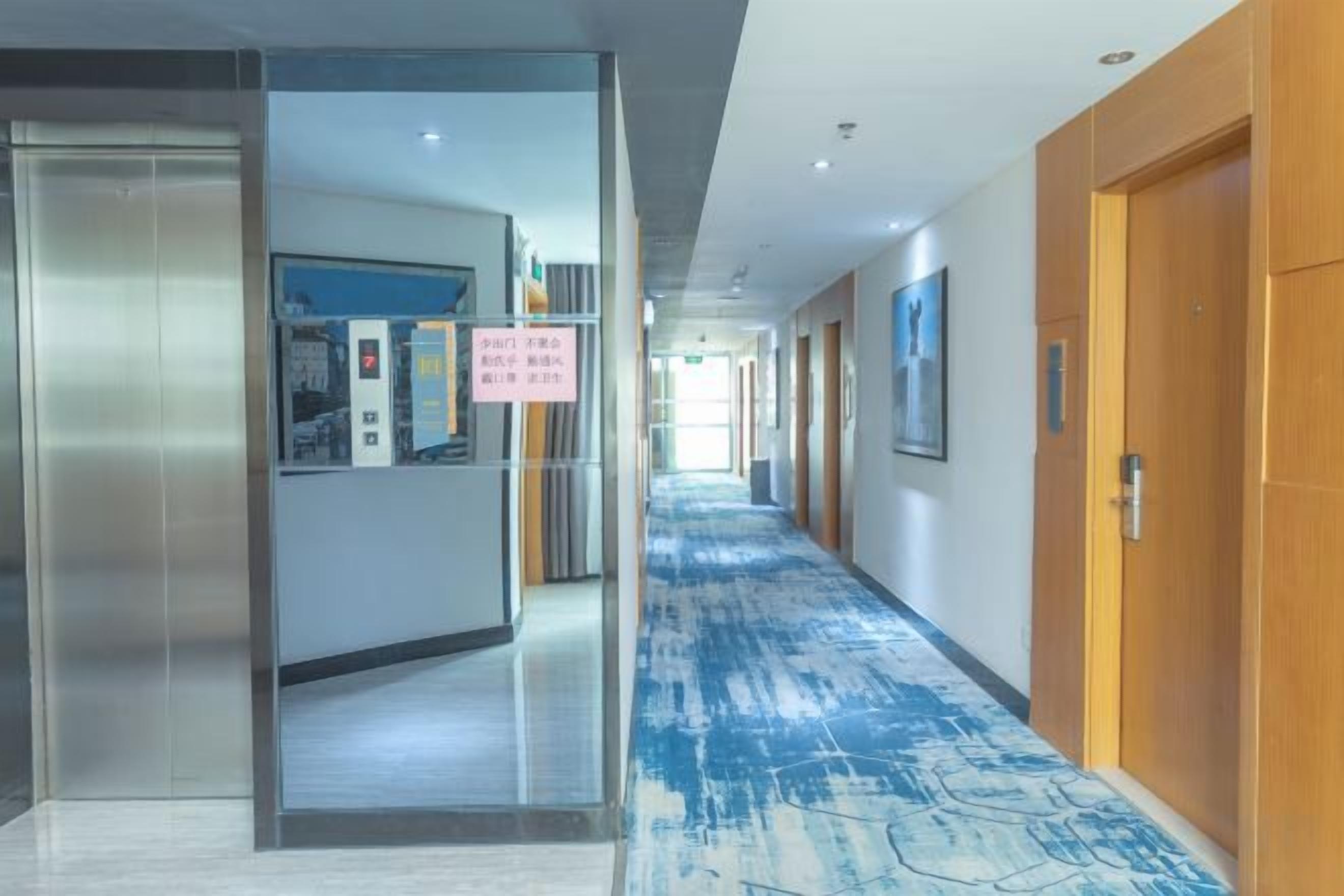 A hotel corridor with a reception desk, a blue patterned carpet, and wooden doors.